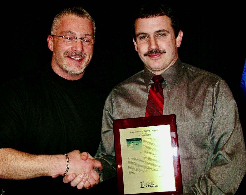 Rigler brothers sharing the celebration of a Legend. Dave, left, presents his older brother Doug with the plaque. Photo by Stan Neufeld